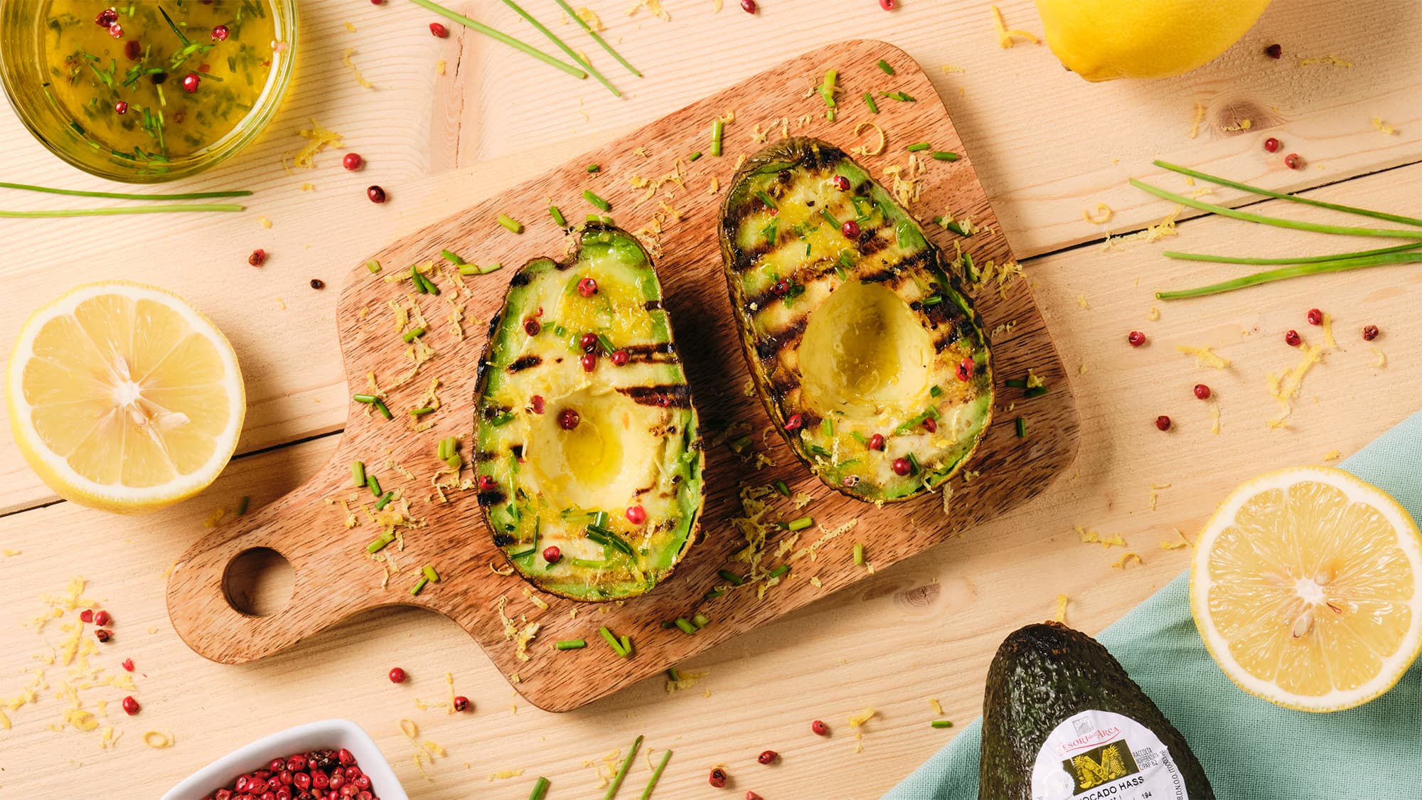 Avocado grigliato con olio aromatizzato all'erba cipollina, pepe rosa e zest di limone